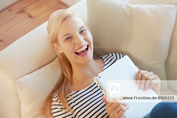 Junge Frau auf Sofa  mit digitalem Tablett