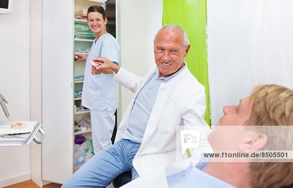 Männlicher Zahnarzt behandelt männlichen Patienten