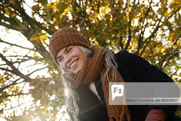 Lächelnde junge Frau im herbstlichen Park eingehüllt