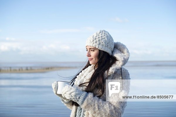 Junge Frau mit Kaffee am Strand  Brean Sands  Somerset  England