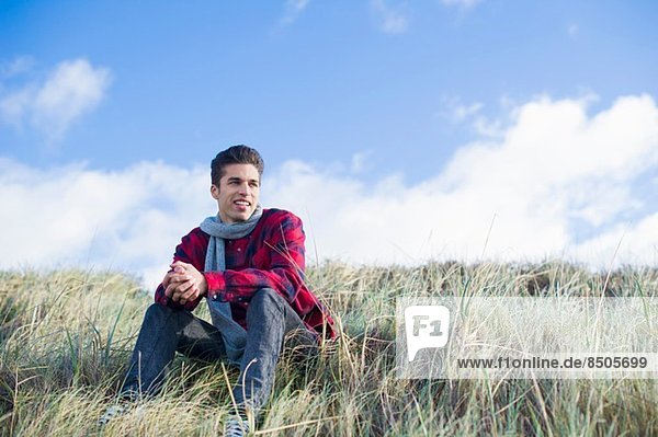 Junger Mann auf Gras sitzend