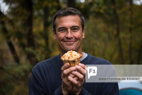 Erwachsener Mann im Wald mit Muffin