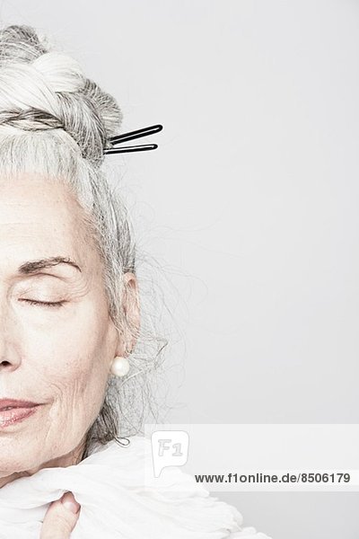 Abgeschnittenes Studioporträt einer älteren Frau mit geschlossenen Augen