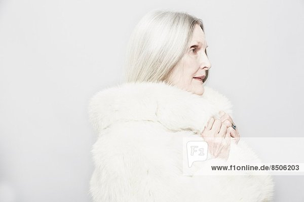 Studio portrait of senior woman in white fur coat