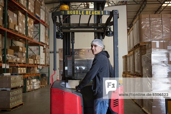 Factory worker with fork lift in warehouse