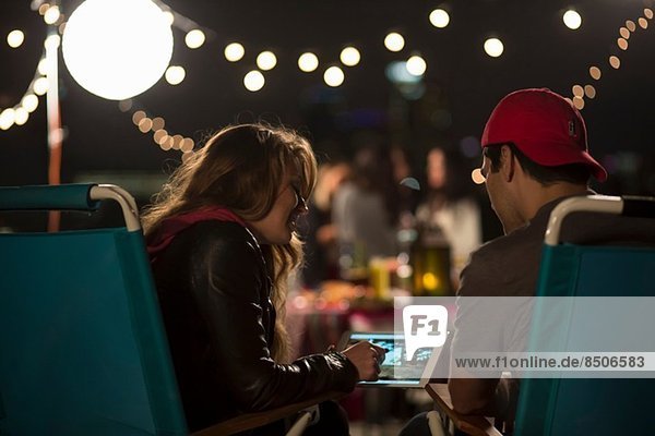 Junges Paar schaut auf digitales Tablett am Dachgrill