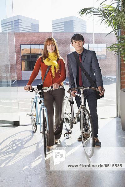 Business people wheeling bicycles in office