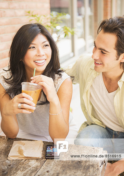 Couple enjoying iced coffee at sidewalk cafe