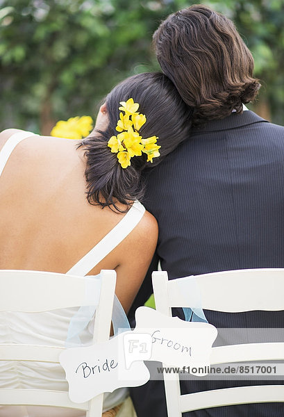 Newlywed couple sitting at wedding reception outdoors
