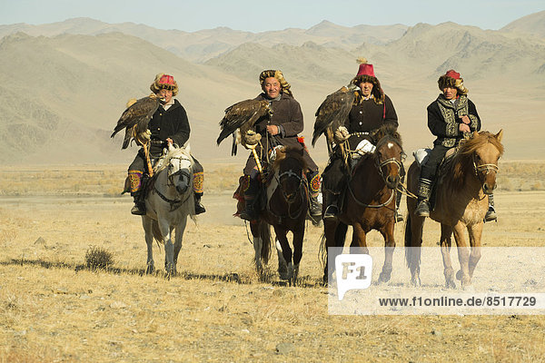Four Kazakh eagle hunters on their horses on the way to the Eagle Festival in Sagsai  Bayan-Oelgii Aimag  Mongolia