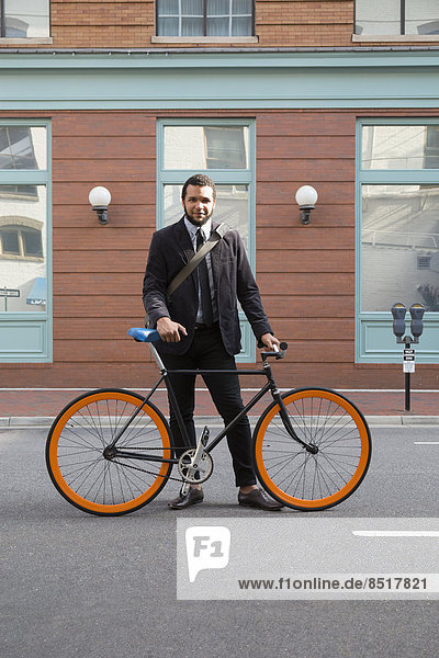 Mixed race businessman with bicycle on city street