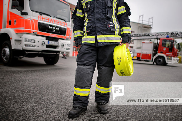 Ein Feuerwehrmann traegt einen Schlauch. Foto: Robert Schlesinger