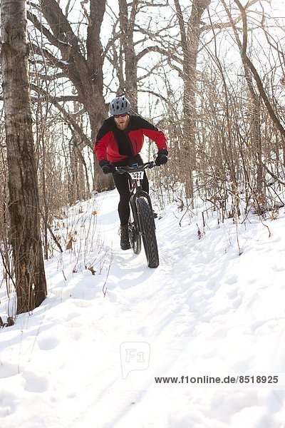 A fat tire biker races along a snowy trail