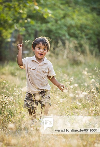 Small boy running through field of grass