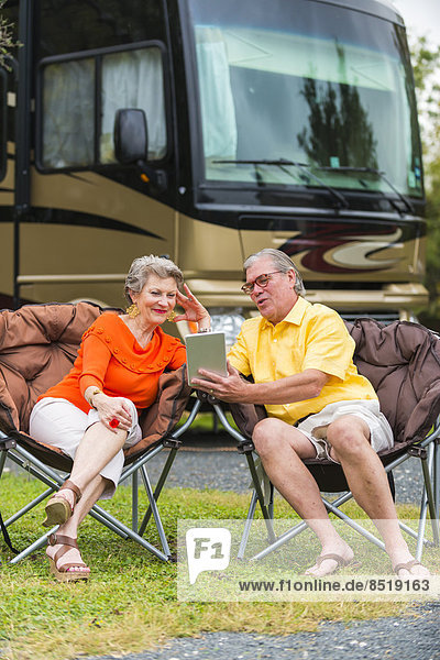 USA  Texas  Seniorenpaar vor ihrem Freizeit-ß-Fahrzeug mit Mini-Tablet PC