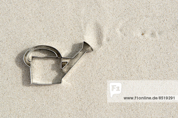 Watering can shaped cookie cutter on sand