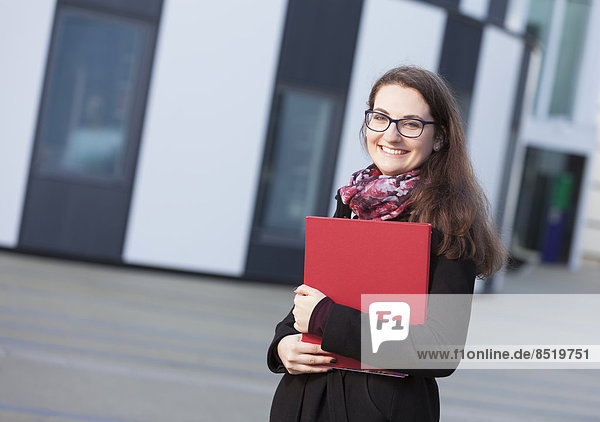 Smiling student with folder outdoors  portrait
