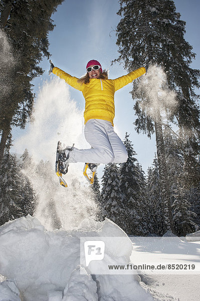 Austria  Salzburg State  Altenmarkt-Zauchensee  Woman with snowshoes jumping in winter landscape