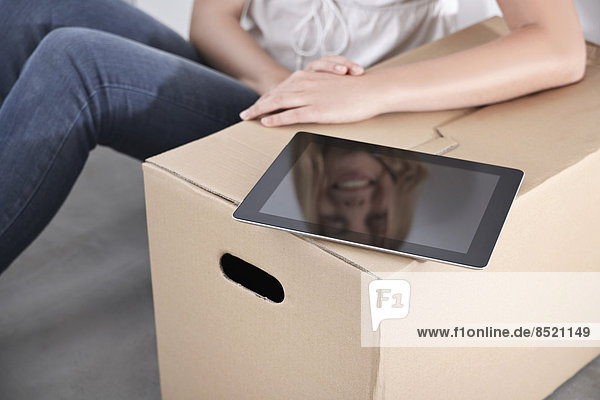 Young woman with cardboard box and tablet computer