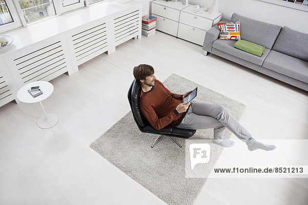 Man using digital tablet  sitting in chair