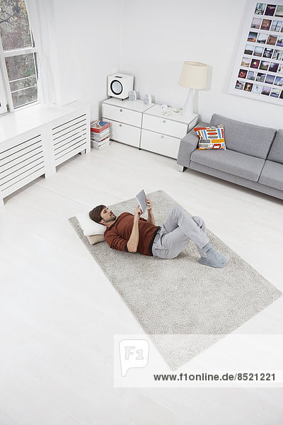 Man lying on floor  using  digital tablet