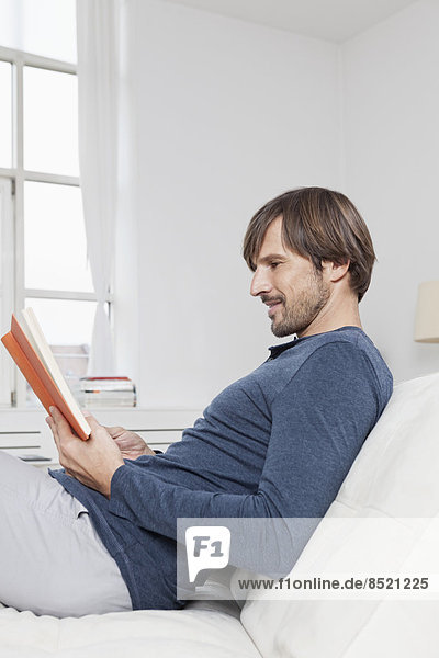 Man sitting on sofa  reading book