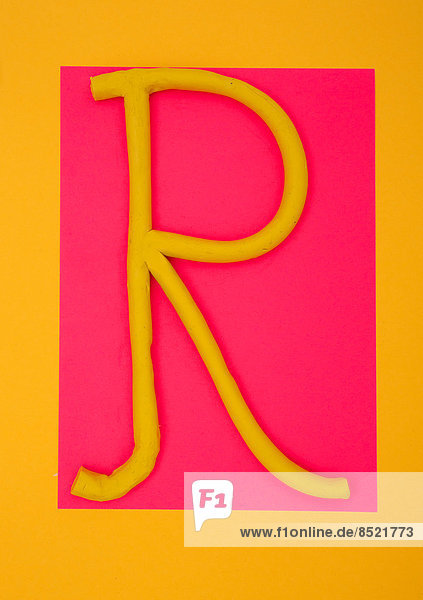 'Letter ''R'' formed of plasticine at pink and yellow background  studio shot'