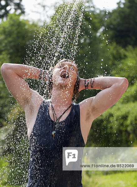 Young man taking a shower in the garden