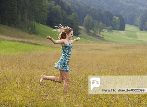 Österreich  Salzkammergut  Mondsee  junge Frau auf einer Wiese laufend