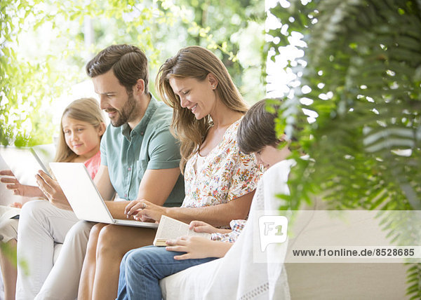 Familie lesen und Technik auf der Terrasse nutzen