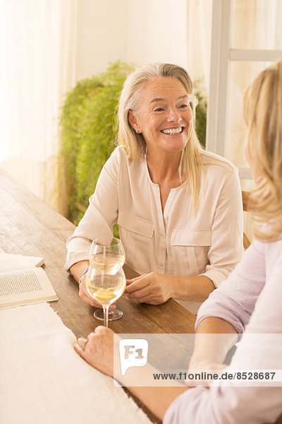 Seniorinnen trinken Weißwein am Esstisch