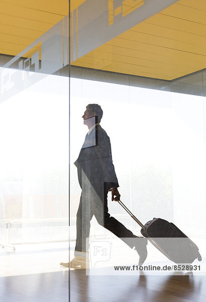 Geschäftsmann zieht Koffer im Flur des Flughafens