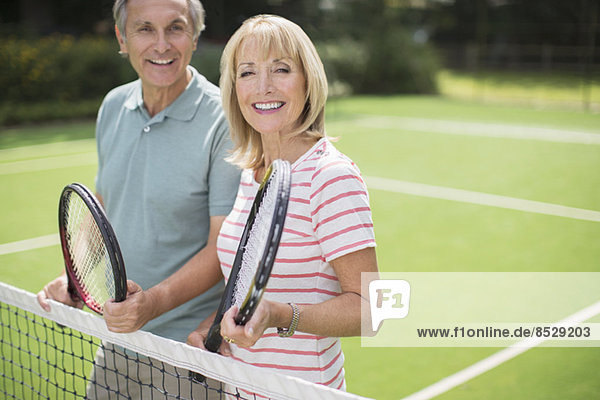 Paar lächelt auf dem Tennisplatz