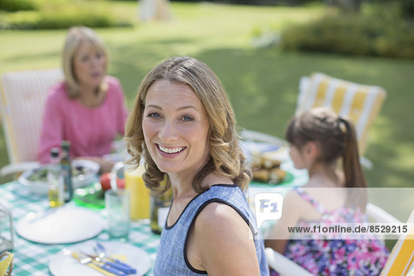 Multi-generation family eating at table in backyard