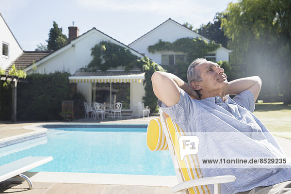 Man relaxing in lounge chair at poolside