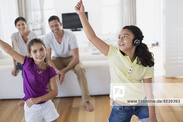 Eltern beobachten Töchter beim Tanzen im Wohnzimmer