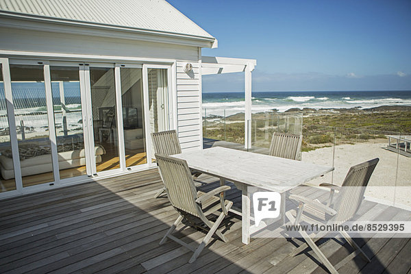 Tisch und Stühle auf dem Balkon mit Blick auf den Strand