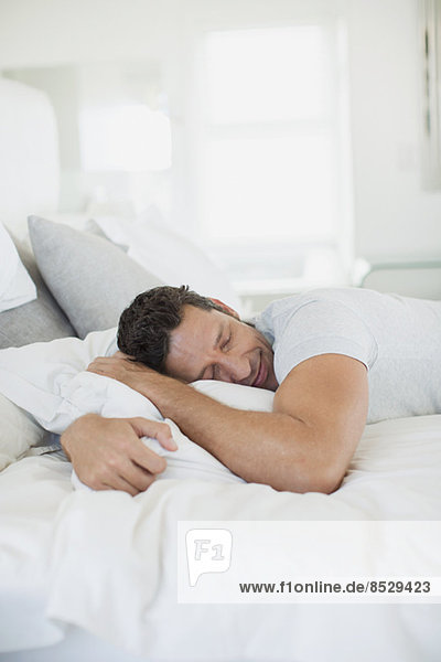Man hugging pillow on bed