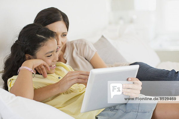 Mutter und Tochter mit digitalem Tablett auf dem Bett