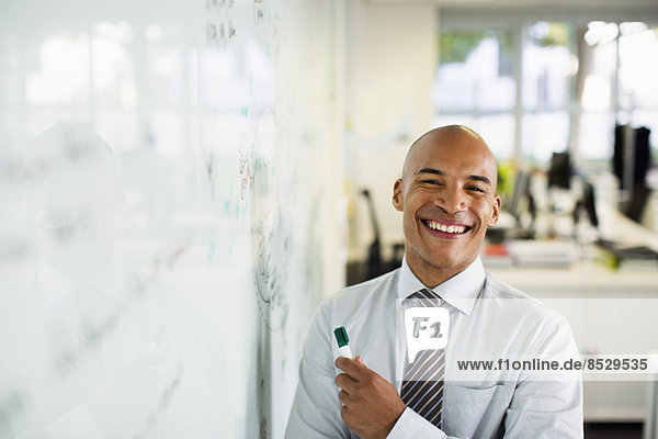 Businessman smiling at whiteboard in office