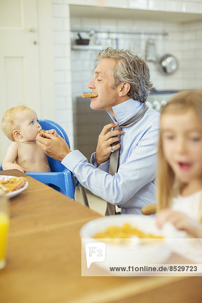 Vater und Kinder beim Frühstücken in der Küche