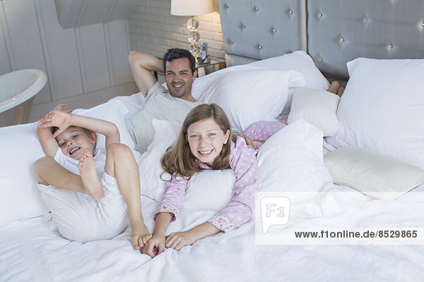 Vater und Kinder entspannen sich auf dem Bett
