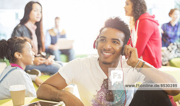 University student listening to headphones in lounge