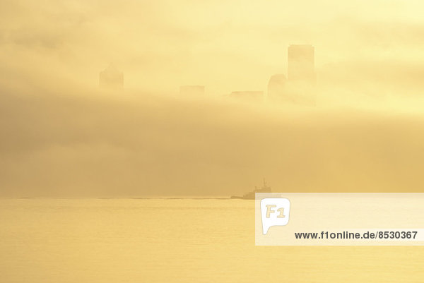 Silhouette von Schlepper und Nebel über der Skyline der Stadt