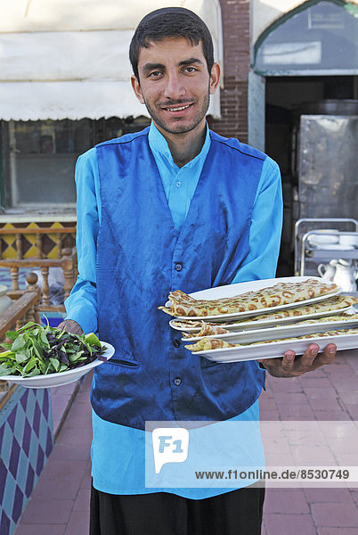 Kellner serviert Brot und Salat in einem traditionellen Restaurant  Basar  Isfahan  Provinz Isfahan  Persien  Iran