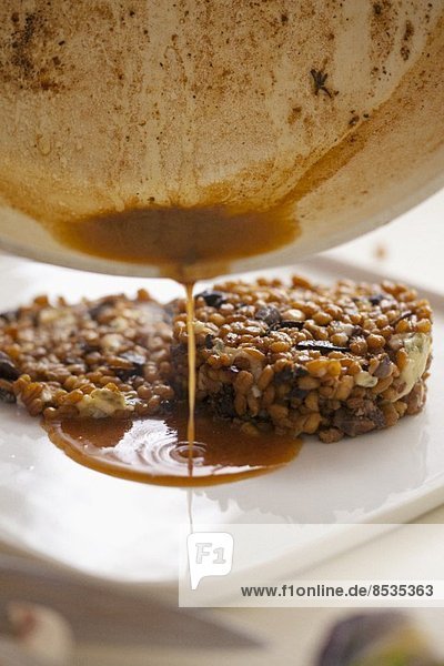 Sauce fließt auf Haferrisotto mit Pilzen und Blauschimmelkäse