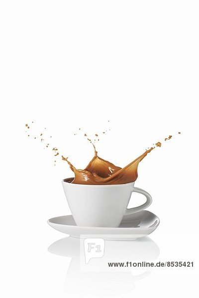 Milchkaffee spritzt aus der Tasse