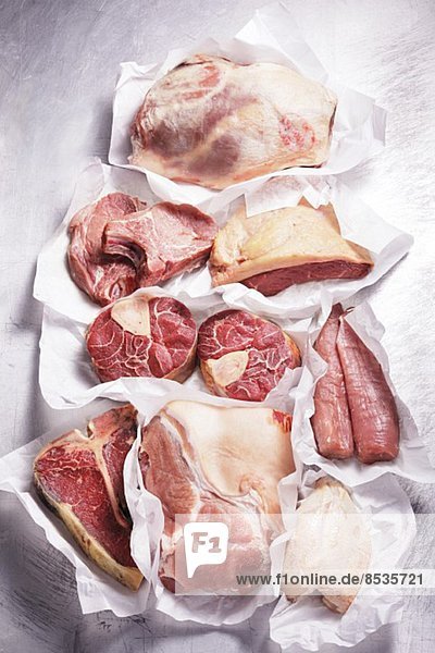 Verschiedene Fleischsorten und Hühnerbrust auf Papier