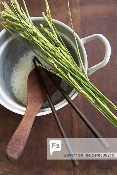 Reis und Ähren  Kochlöffel und Essstäbchen im Reiskochtopf