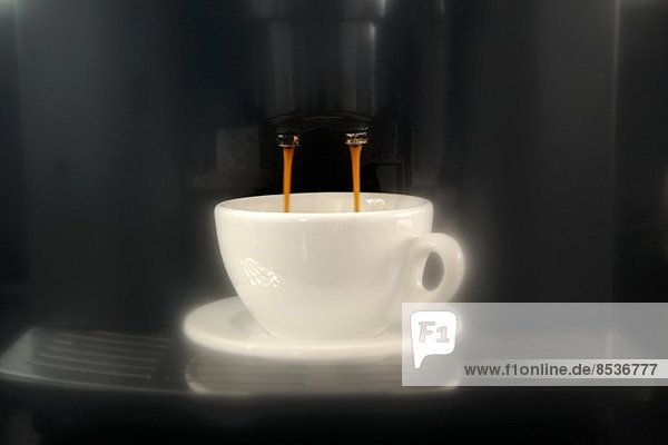 Kaffee fliesst aus der Espressomaschine in die Tasse